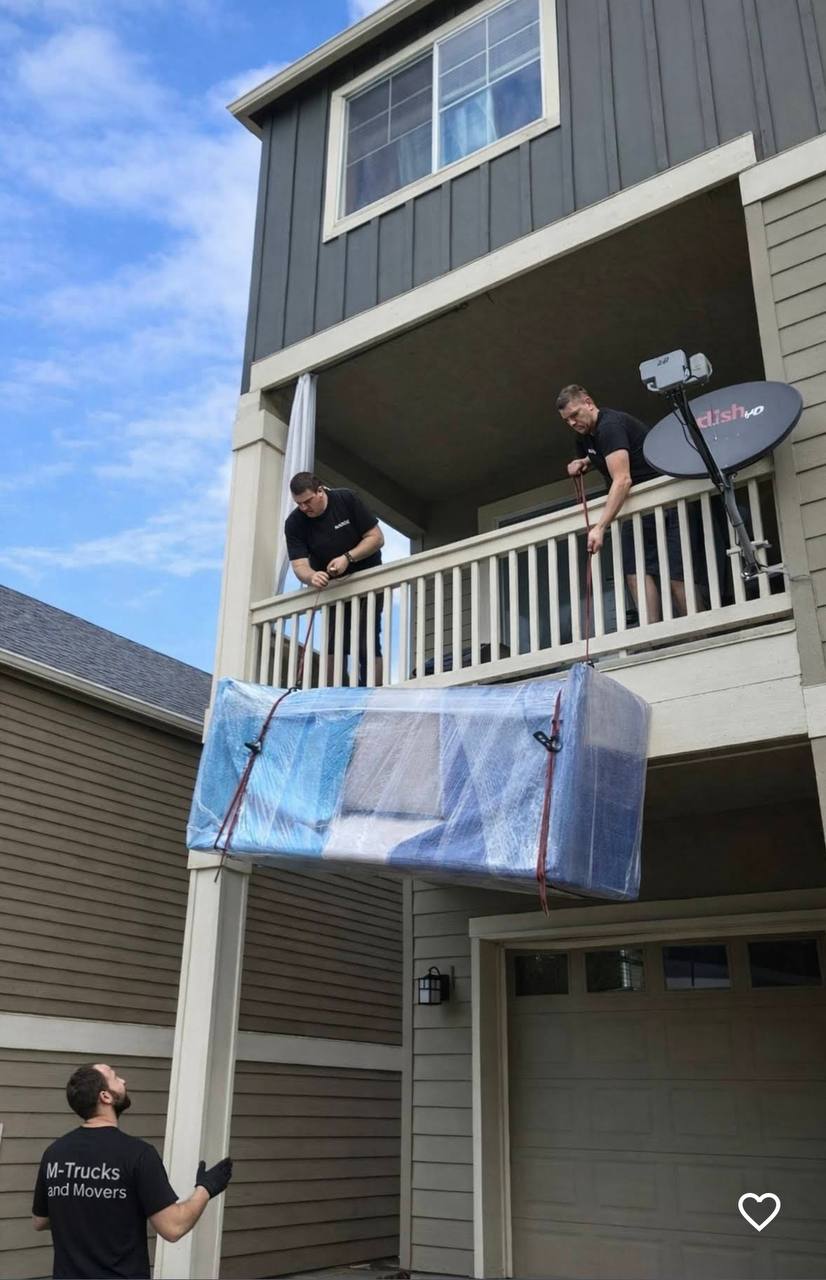 M-Trucks and Movers crew carefully lowering wrapped furniture from a second-floor balcony